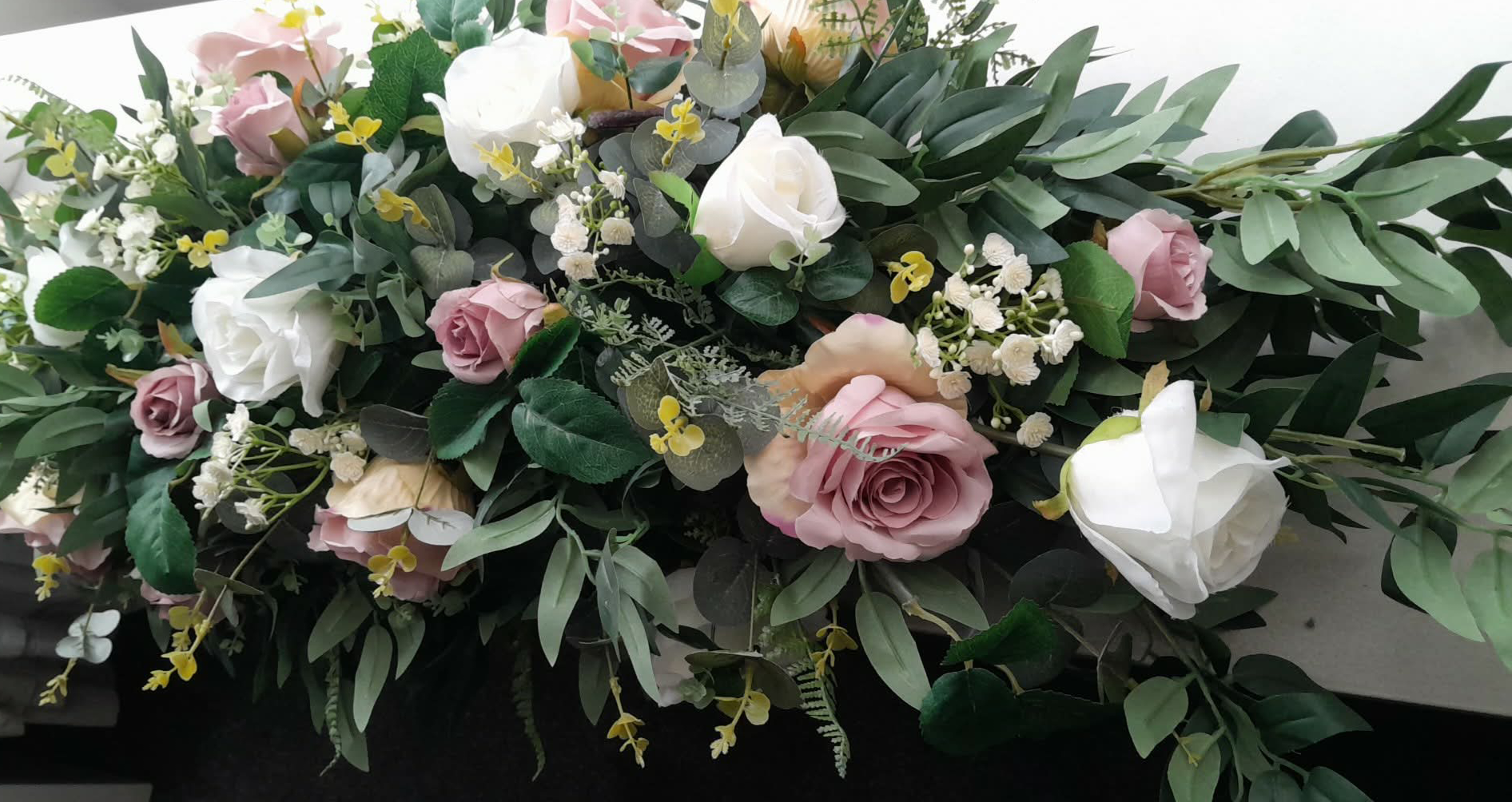 Deluxe top table arrangement with dusky pink and white roses and lush greenery, close up view