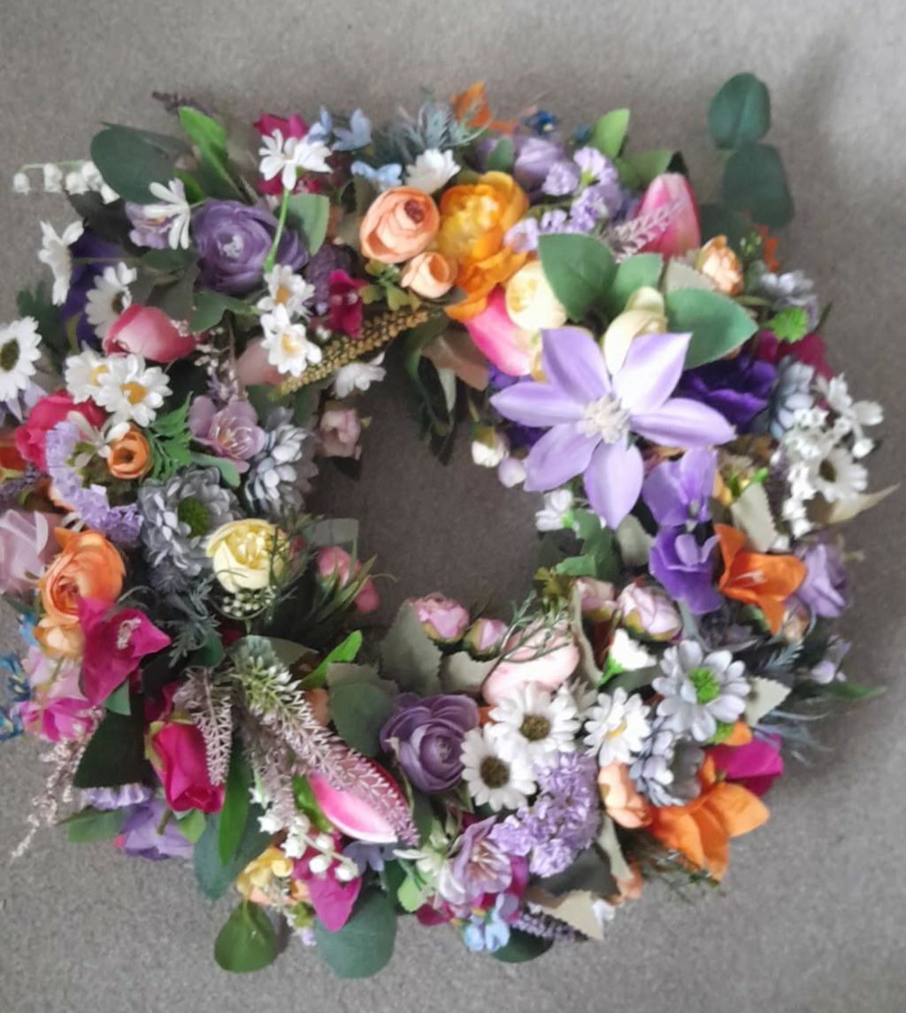 Rainbow Meadow Spring Wreath close-up showing purple clematis, orange roses and white daisies