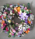 Rainbow Meadow Spring Wreath close-up showing purple clematis, orange roses and white daisies