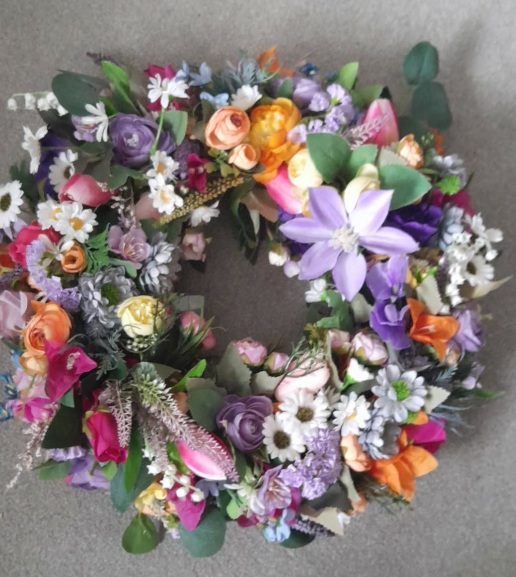 Rainbow Meadow Spring Wreath close-up showing purple clematis, orange roses and white daisies