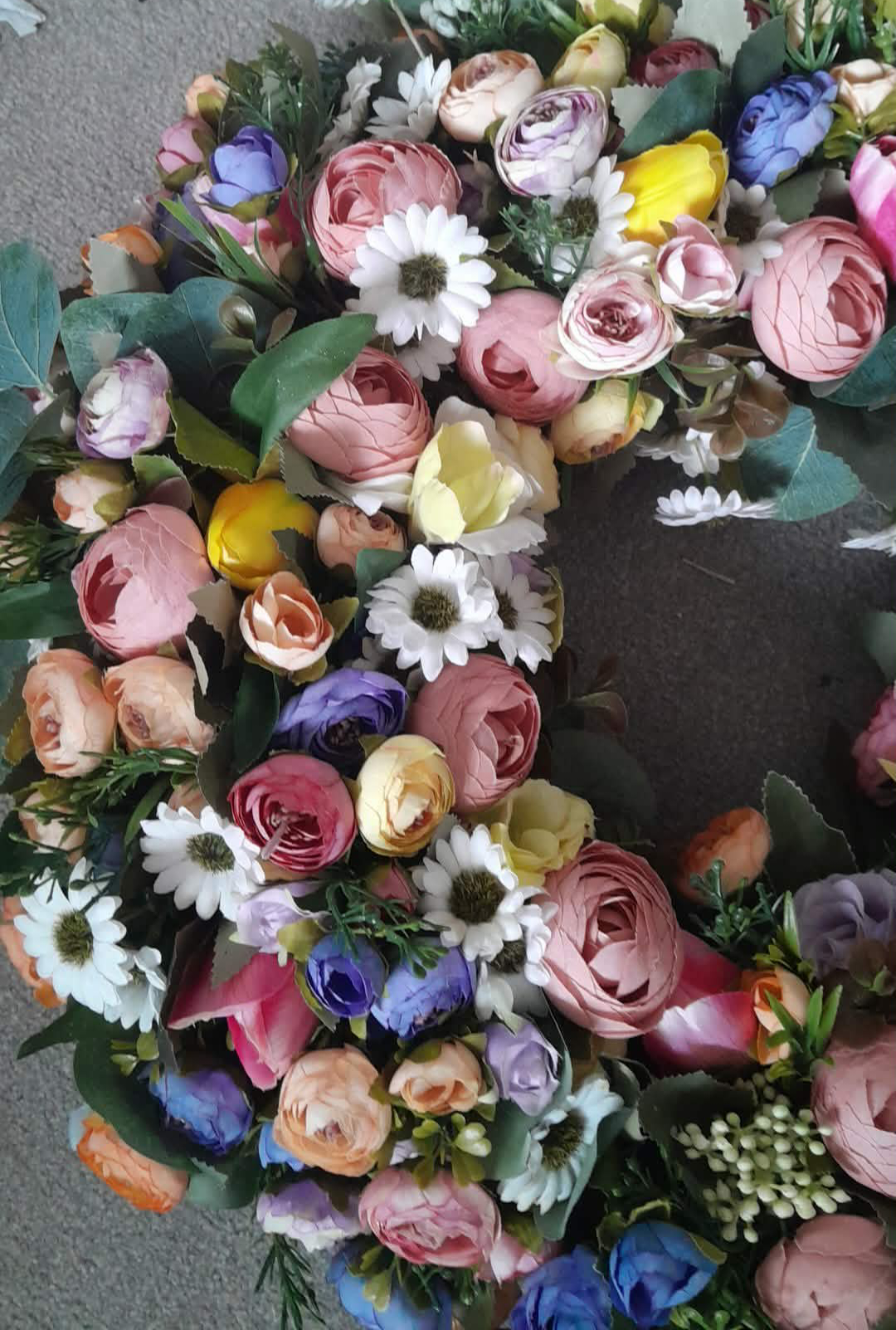 Close-up detail of spring summer mixed flower wreath showing ranunculus, roses and daisy blooms