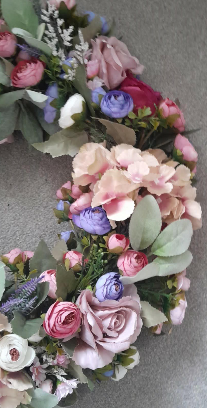 Close-up detail of pastel floral wreath showing blush hydrangeas and dusky rose ranunculus