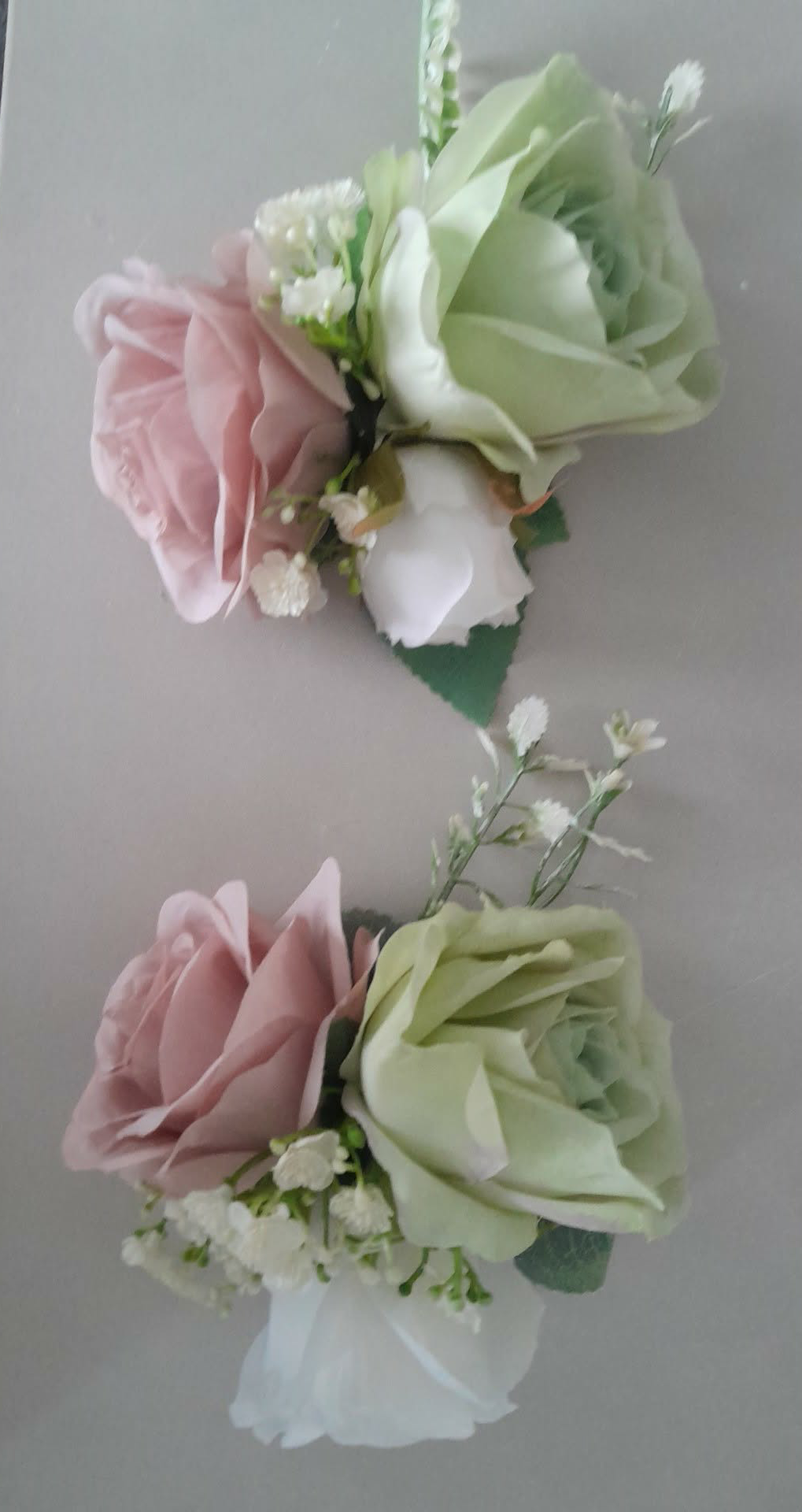 Freya collection dusky pink rose buttonholes and corsages laid flat on a grey surface