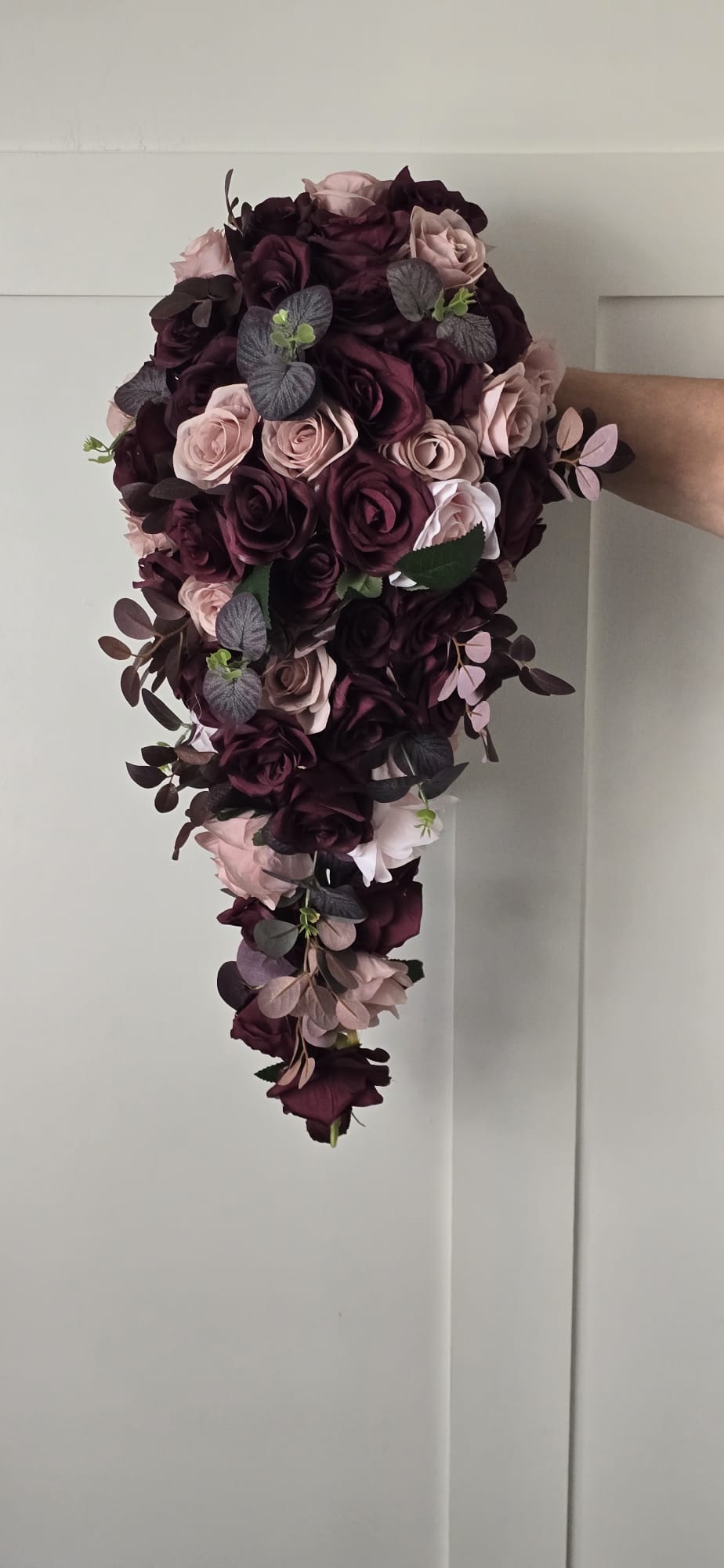 Aoife XXL cascading bridal bouquet featuring deep plum and blush roses with eucalyptus, held against a white wall