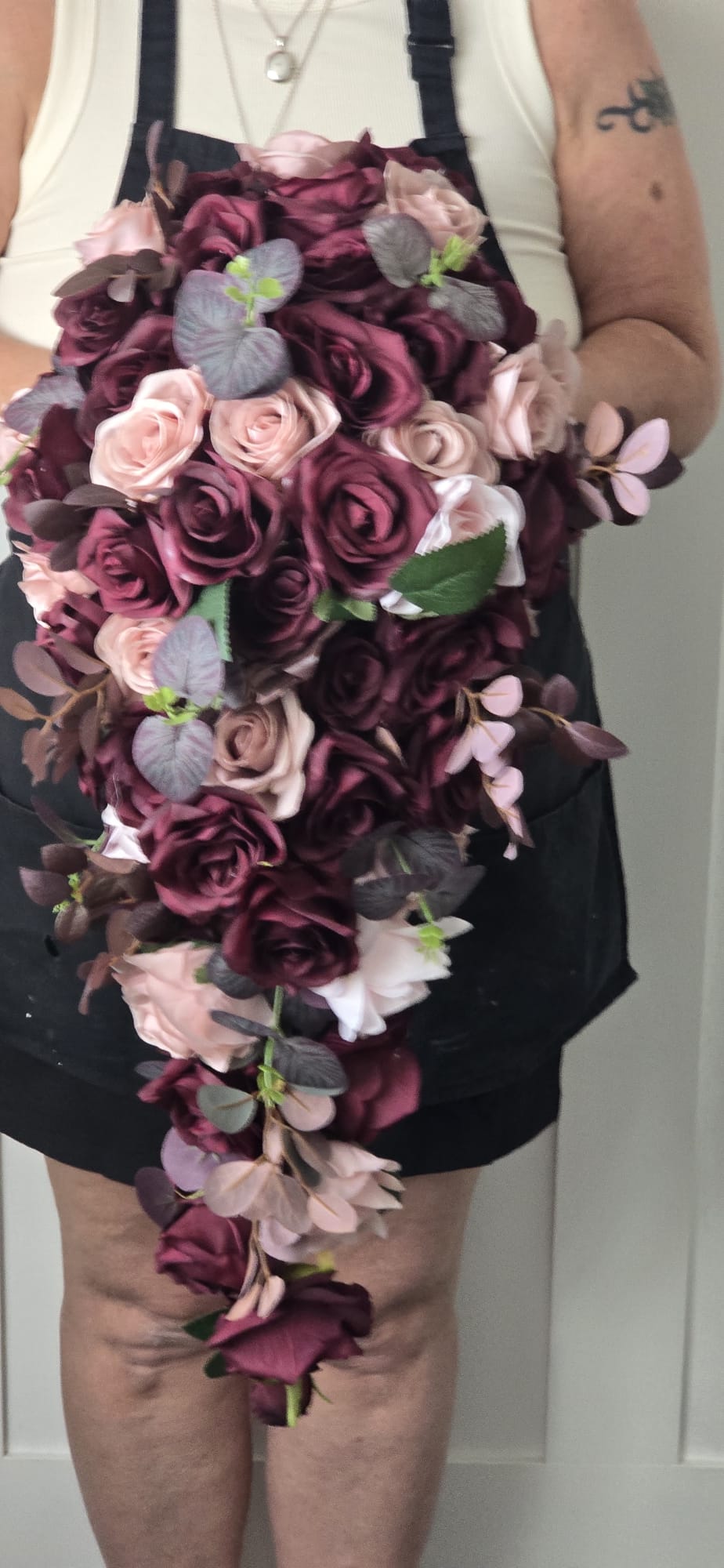 Aoife XXL cascading bridal bouquet held by bride showing full length of 27 inch cascade with plum and blush roses