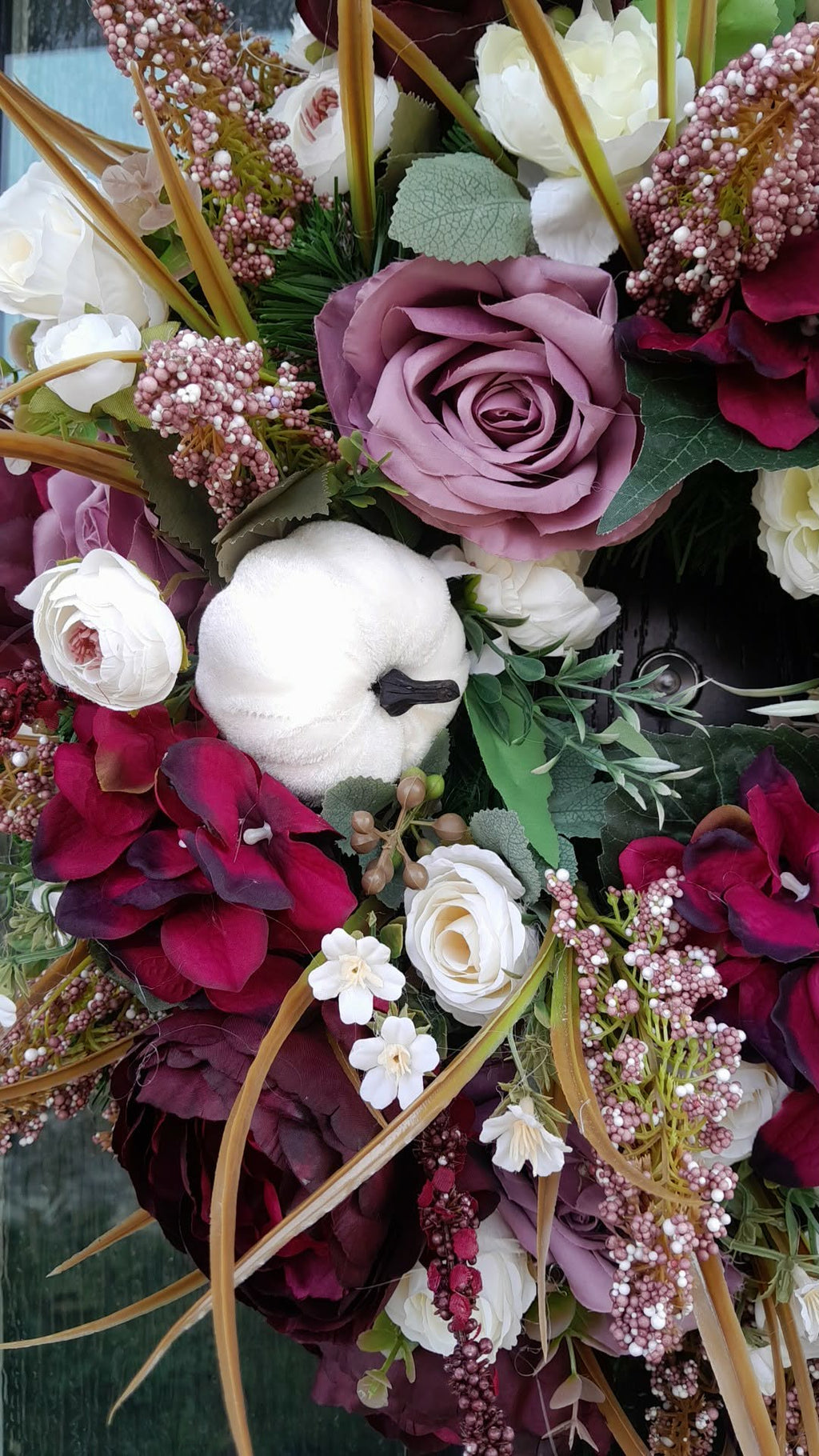 Close-up detail of Autumn Burgundy and Mauve Luxury Wreath showing burgundy hydrangeas, mauve roses, white ranunculus, blush berry clusters and golden grasses