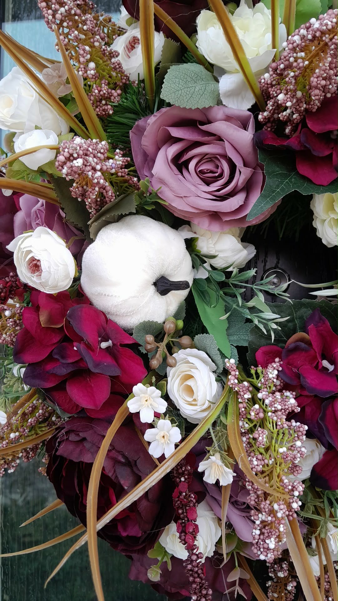 Close-up detail of Autumn Burgundy and Mauve Luxury Wreath showing burgundy hydrangeas, mauve roses, white ranunculus, blush berry clusters and golden grasses