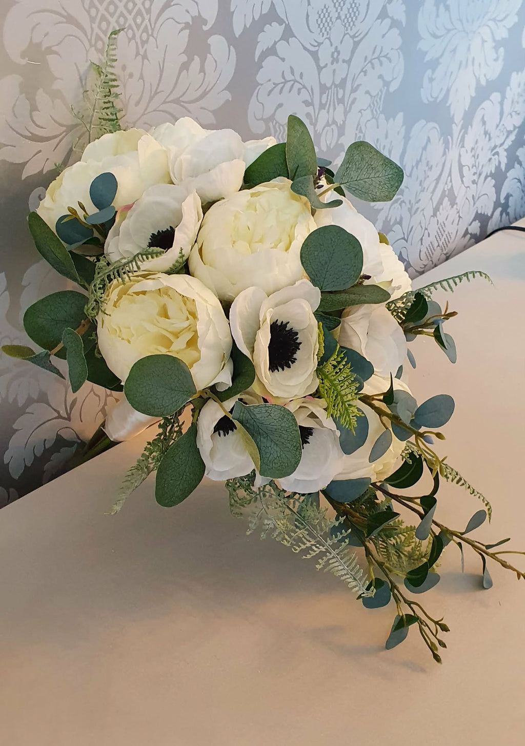 Thessaly cascading bridal bouquet — angled view on ivory fabric surface