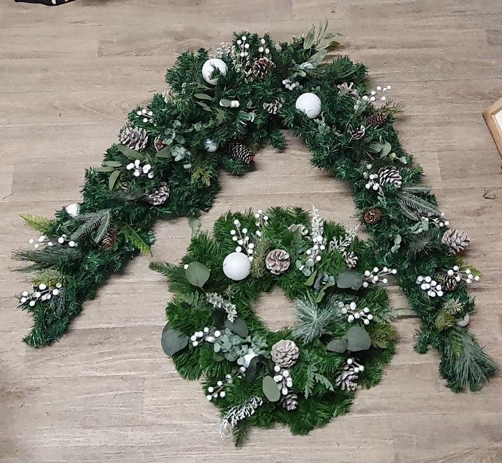Natural green and white Christmas full door garland set with matching wreath laid out on a wooden floor, featuring mixed pine, eucalyptus, white berries and pine cones