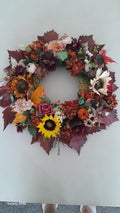 Close-up detail of Sunflower & Pumpkin Autumn Wreath showing cream sunflower, orange pumpkins, burgundy hydrangeas, pine cones and maple leaves