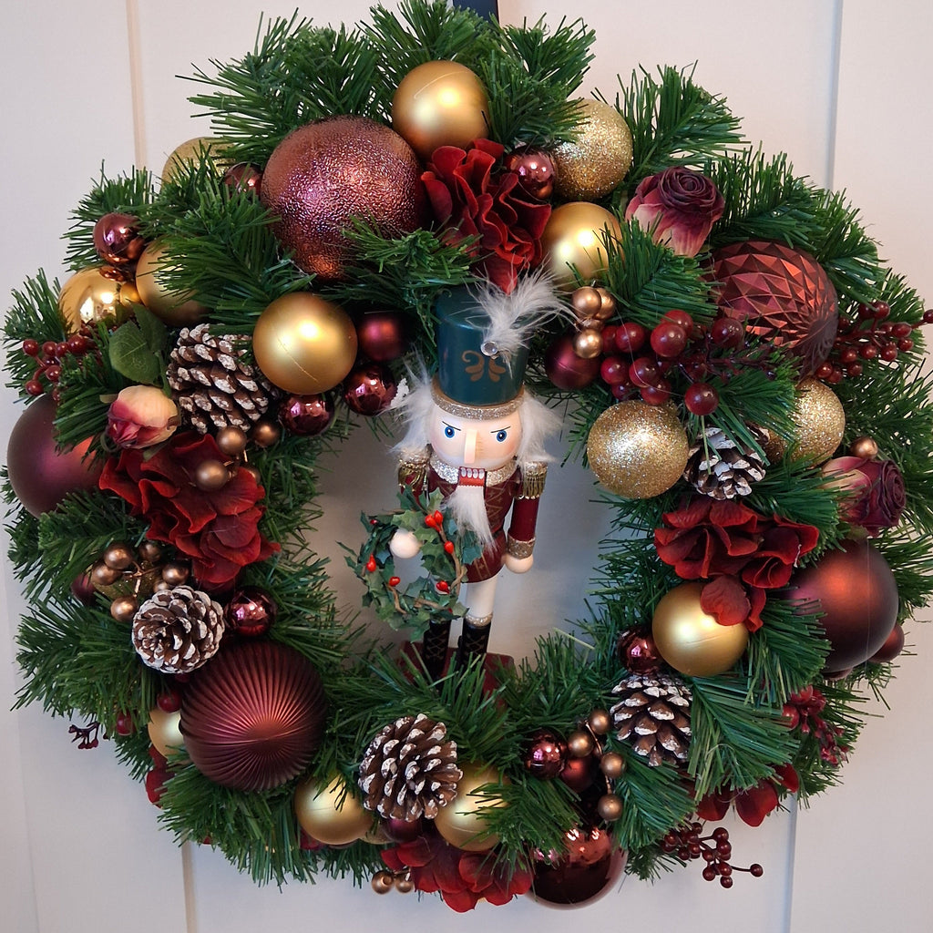 Vespera 20-inch burgundy and gold Christmas wreath with nutcracker, baubles, flowers and white-tipped pine cones