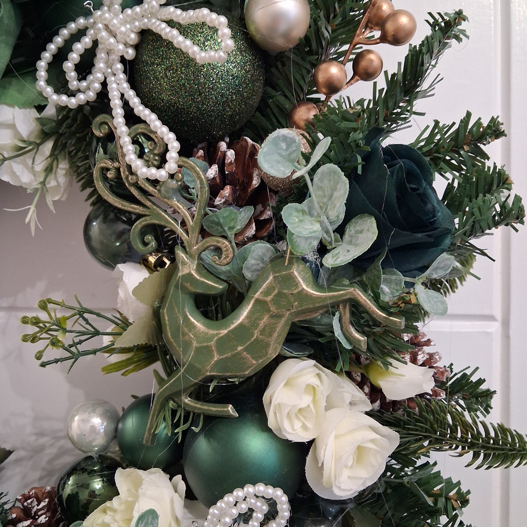 Close-up of Christmas wreath with green reindeer decoration, ivory flowers and pearl-style bow