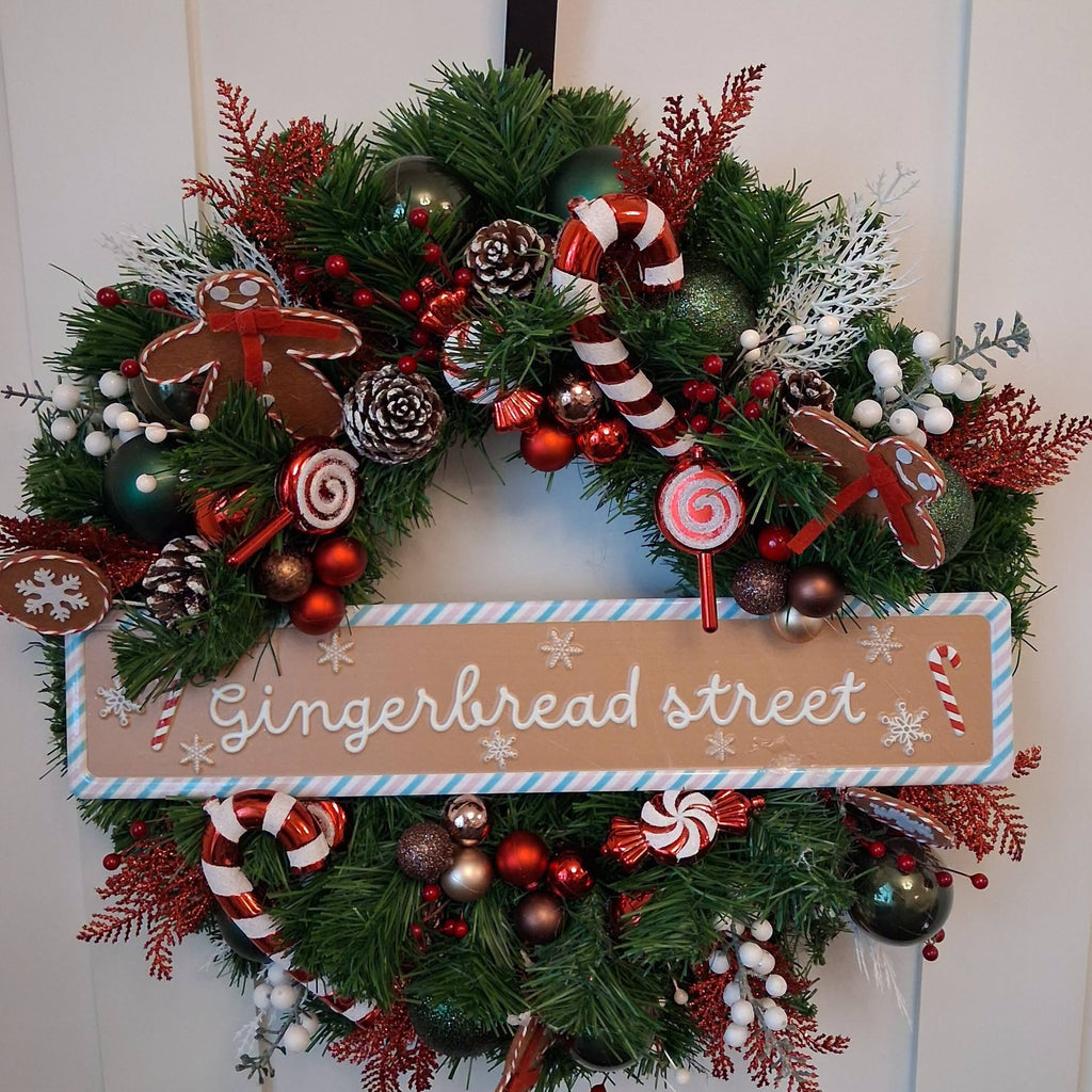20-inch Gingerbread Street Christmas wreath with gingerbread figures, candy canes, red and green baubles and snowy pine cones