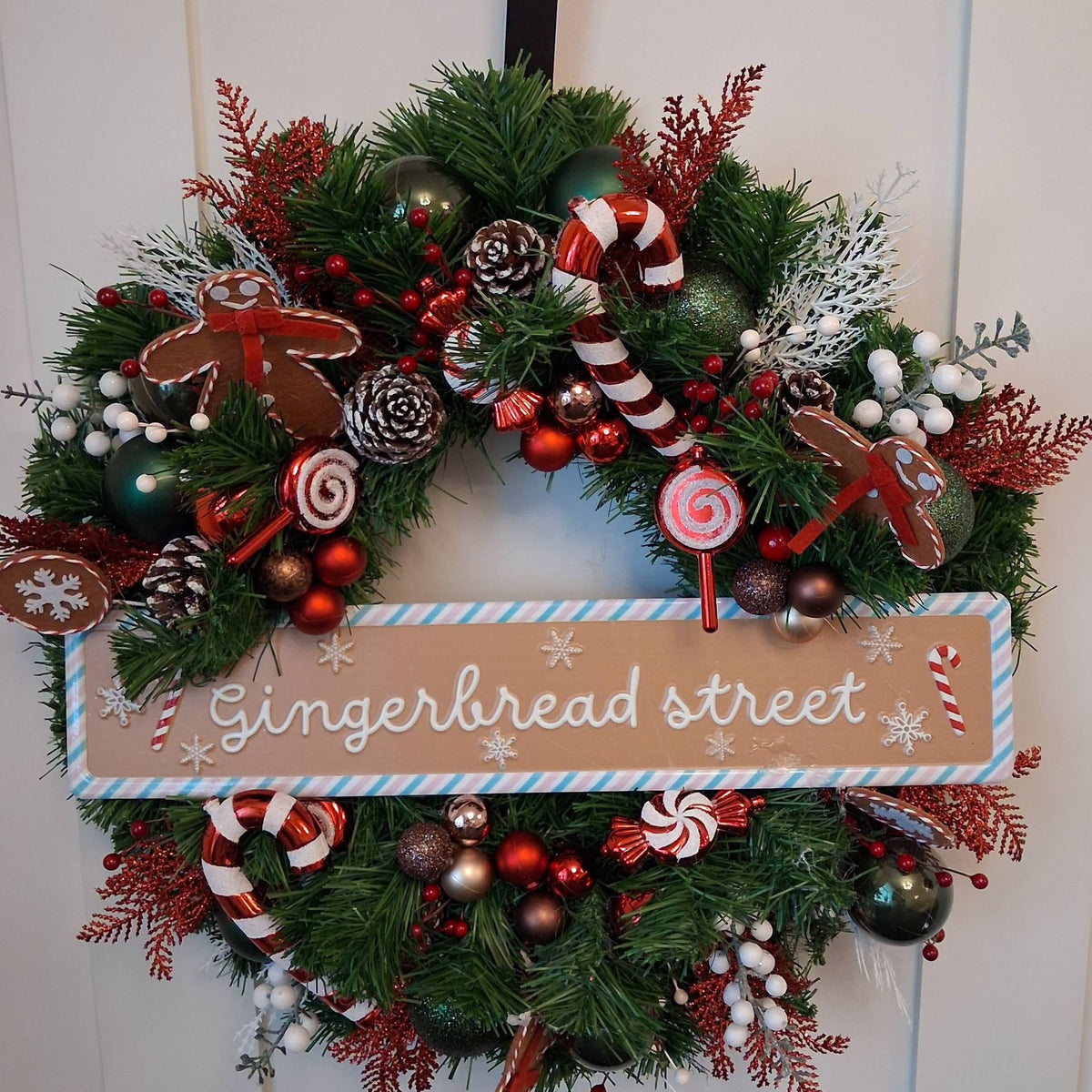 20-inch Gingerbread Street Christmas wreath with gingerbread figures, candy canes, red and green baubles and snowy pine cones