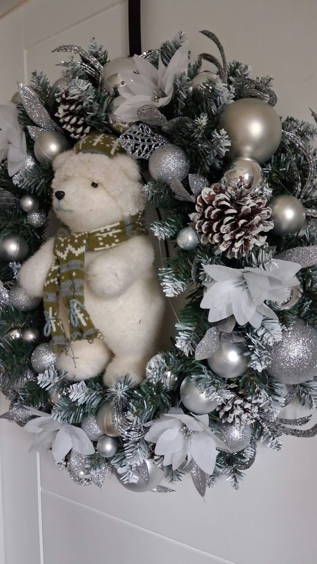 Side view of silver and white polar bear Christmas wreath showing frosted foliage, pine cones and silver decorations