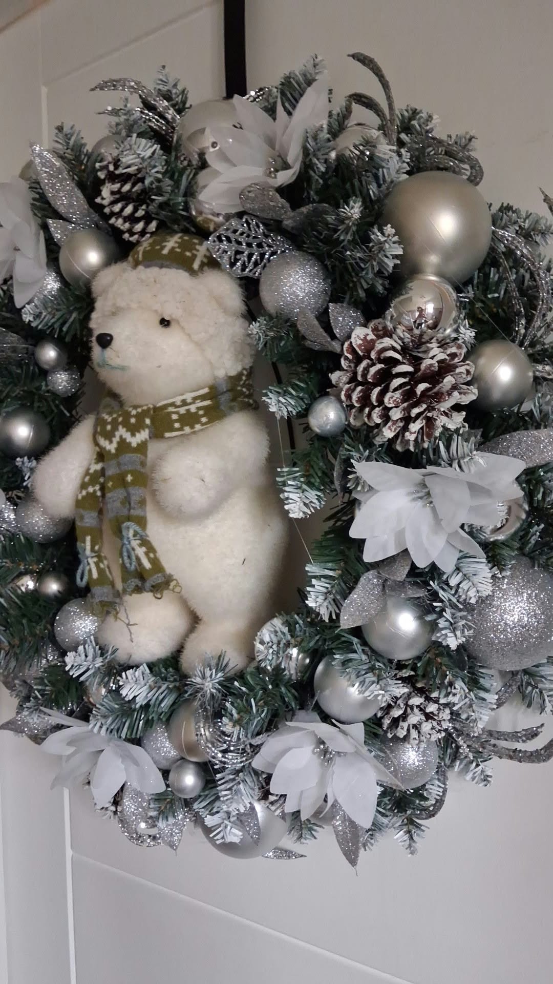 Side view of silver and white polar bear Christmas wreath showing frosted foliage, pine cones and silver decorations