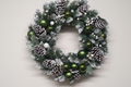 50cm frosted green and white Christmas wreath with forest green baubles, frosted pine cones and white berry clusters on a white background