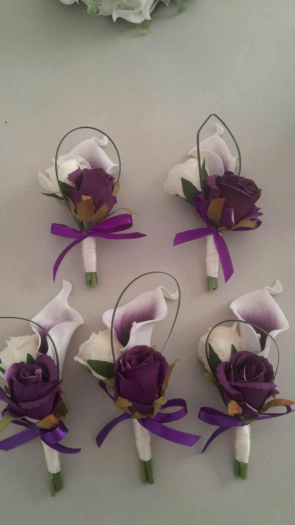 Isolde silk wedding buttonholes in deep purple and white with purple ribbon by Boutique Bouquets
