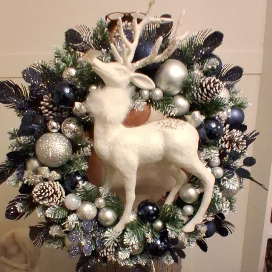 Close view of white stag centrepiece surrounded by navy and silver decorations and frosted foliage